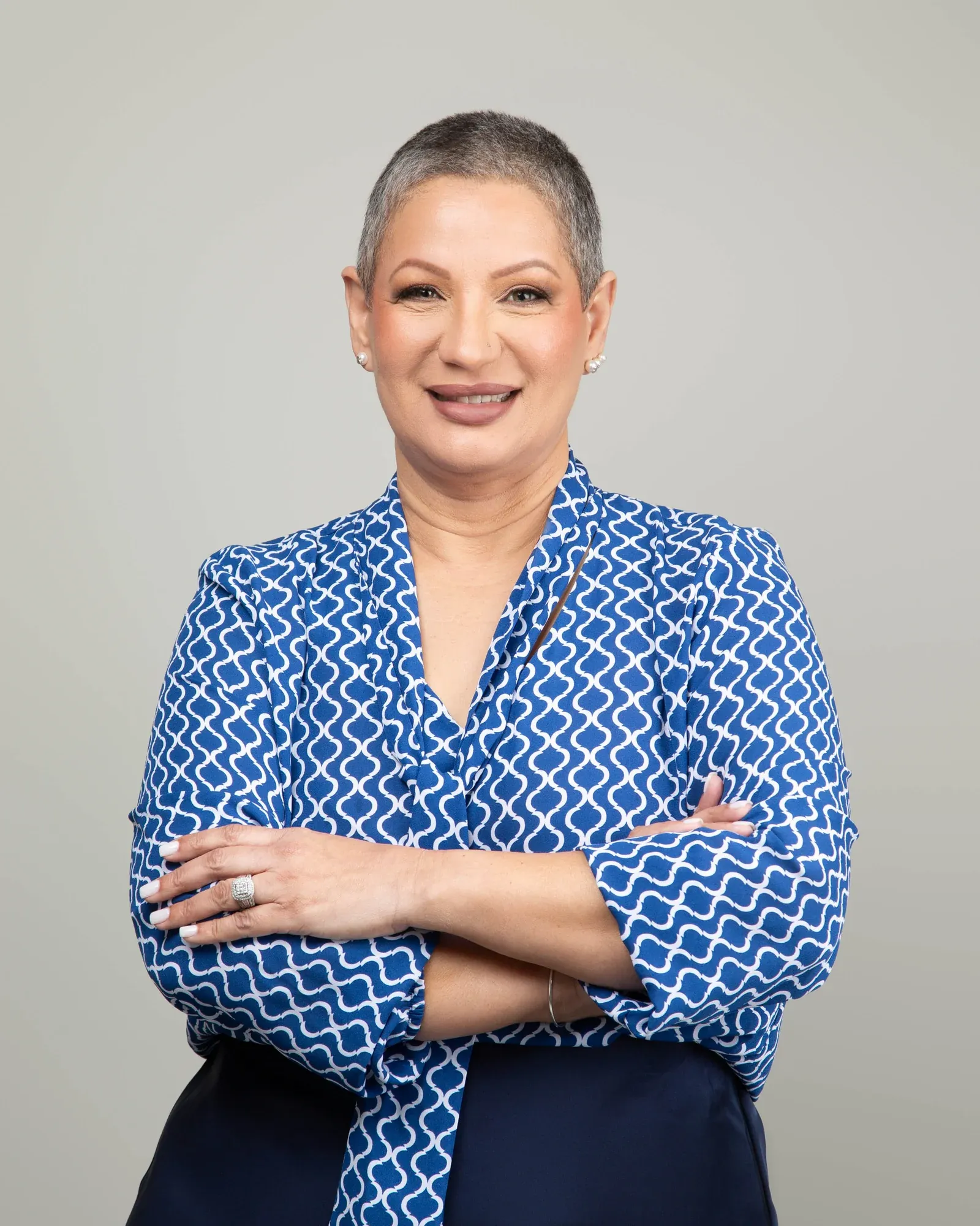Isis García, fundadora de Insurance & Tax Solutions, con blusa azul y los brazos cruzados